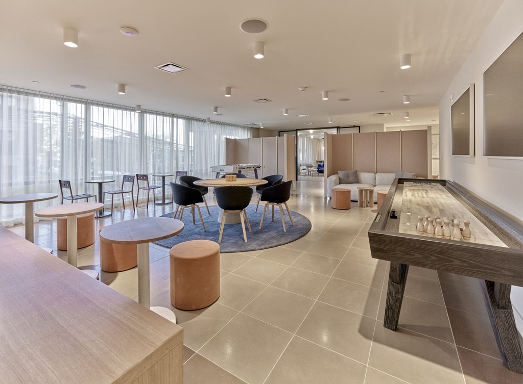 a common room with tables and chairs and a shuffleboard