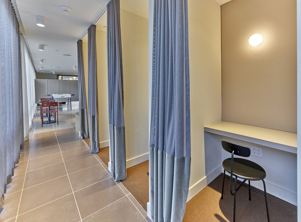 a corridor with blue curtains and a table and chairs in a hotel room