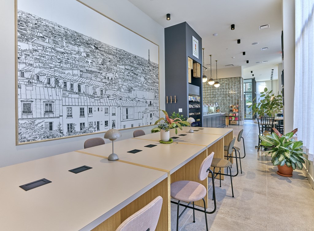 a long communal table with chairs in a room with a bar and a wall mural