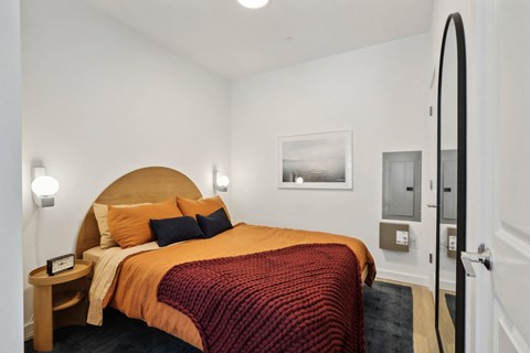 a bed in a hotel room with a red blanket and orange pillows