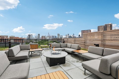 a rooftop patio with couches and tables and a view of the city