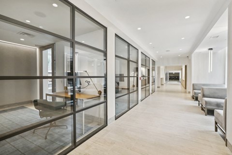 a long hallway with glass doors and chairs and a table