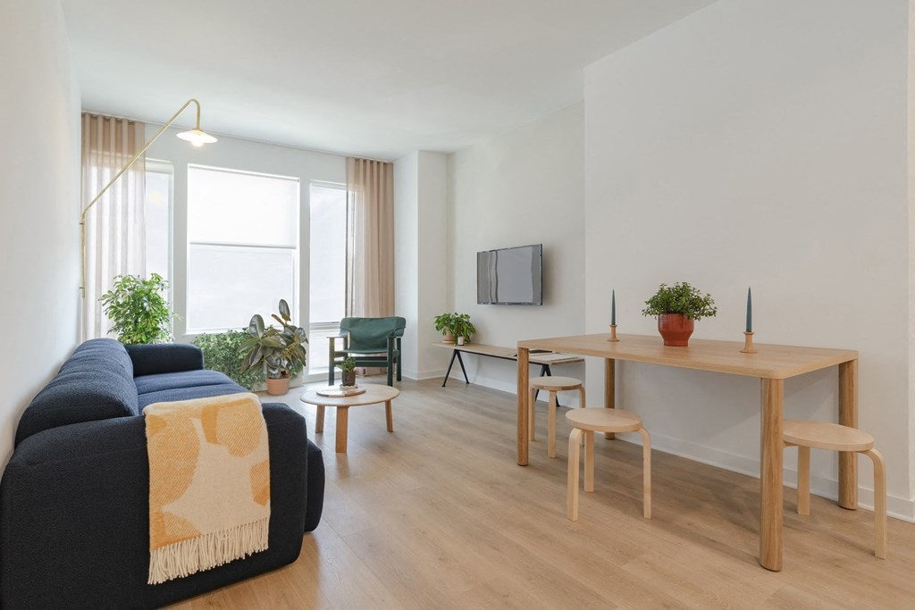 a living room with a couch a table and chairs and a tv on the wall