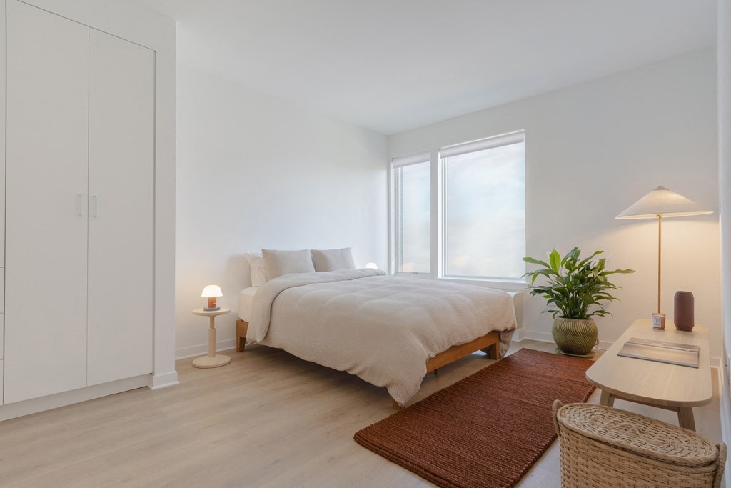 a bedroom with white walls and white bedding
