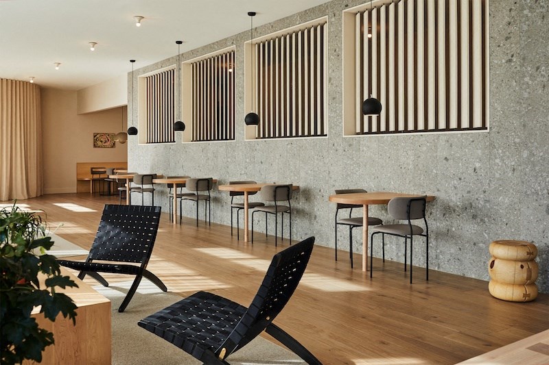 a dining area with tables and chairs and a wall of windows