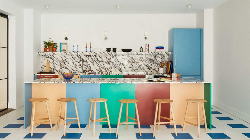 a colorful kitchen with a marble countertop and colorful stools