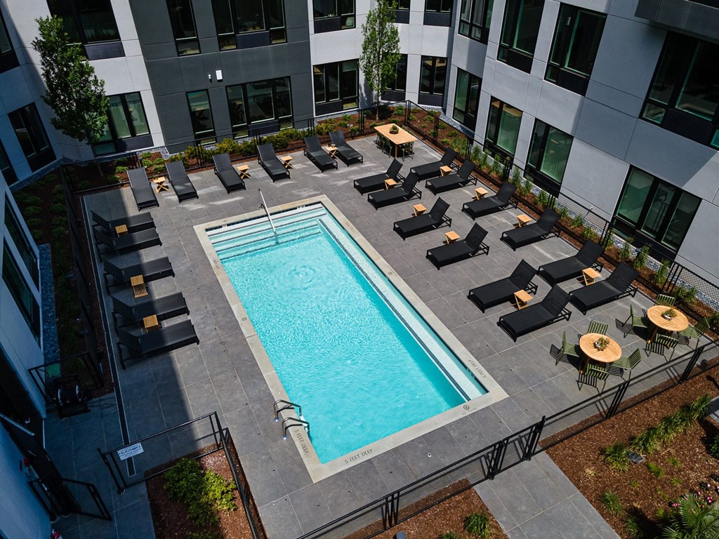 an aerial view of a swimming pool with lounge chairs and umbrellas in front of a