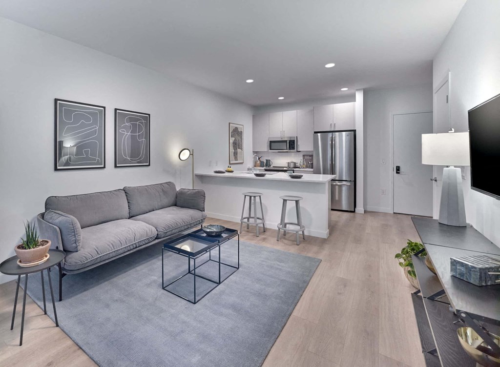 a living area with a couch coffee table and a kitchen in the background