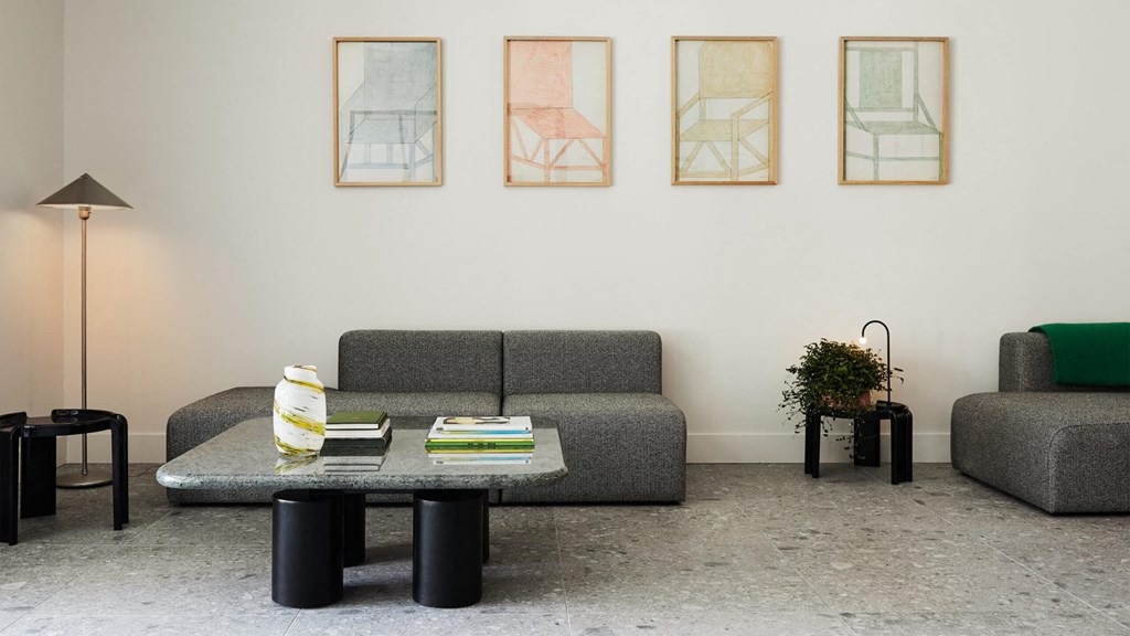 a living room with a grey couch and three paintings on the wall