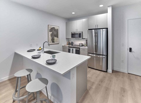 a kitchen with a white counter top and a stainless steel refrigerator
