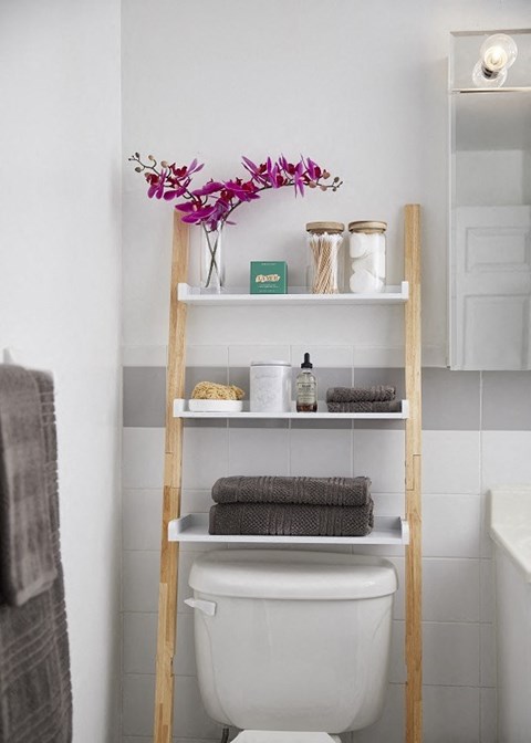 a ladder in a bathroom with towels on it and a vase with purple flowers on top