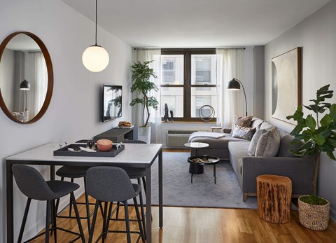 A modern living room with a dining table and grey couch.