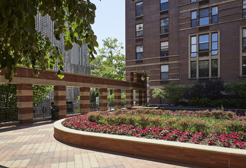 a planter filled with flowers in front of a brick building