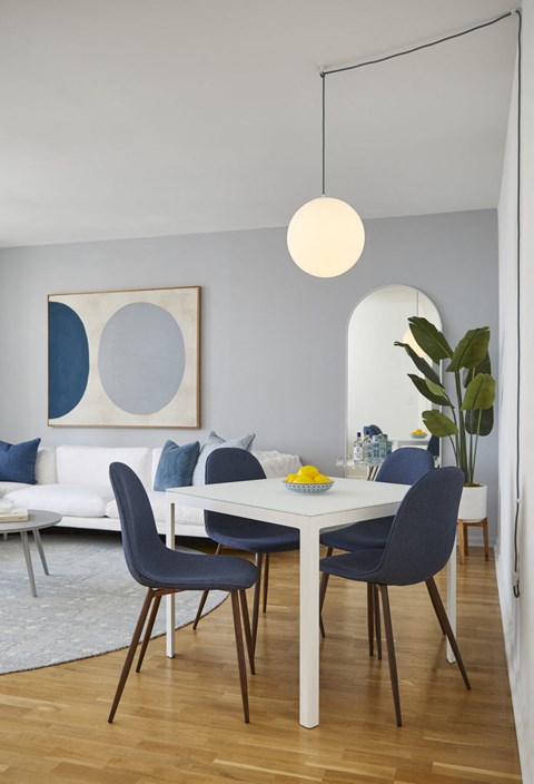 a dining area with a white table and blue chairs and a white couch in the background