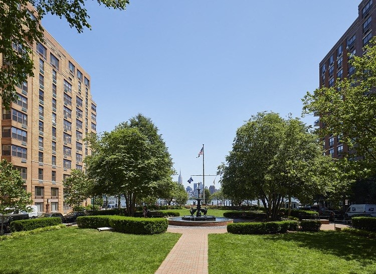 a fountain in the middle of a grassy area between two buildings