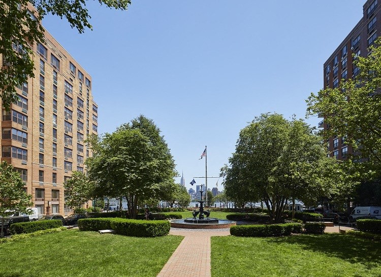 a fountain in the middle of a grassy area between two buildings