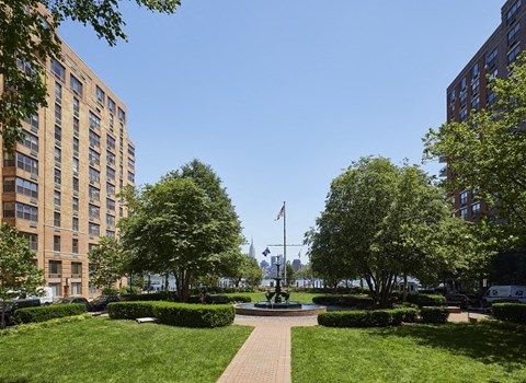 a fountain in the middle of a grassy area between two buildings