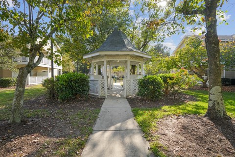 A gazebo is surrounded by trees and bushes.