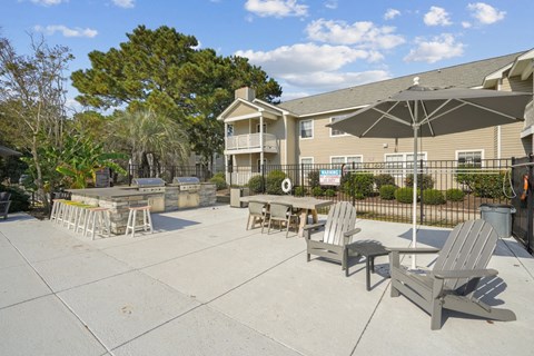 A patio with chairs and an umbrella in front of a building.