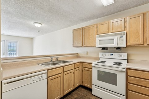 A kitchen with a white stove and wooden cabinets.