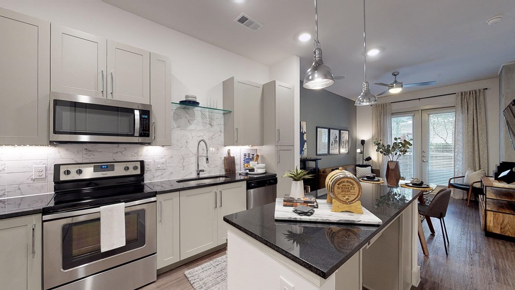 Kitchen with wood cabinets and stainless steel appliances facing bar area and living room from entry door