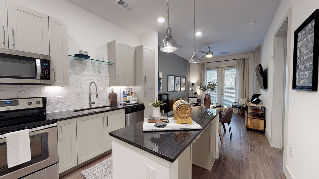 Kitchen with wood cabinets and stainless steel appliances facing bar area and living room from entry door