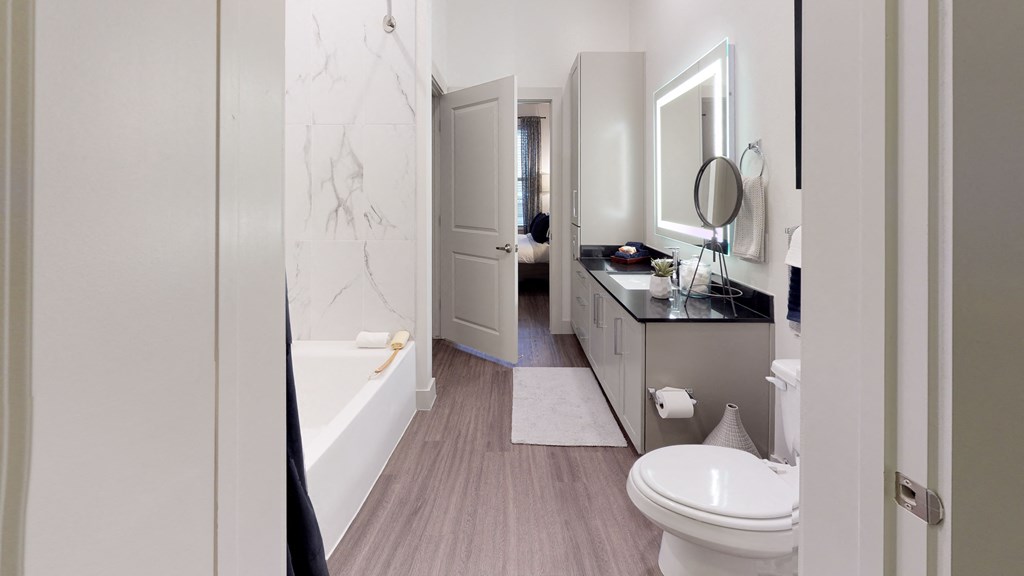 Bathroom facing sink with cabinets underneath, toilet and shower