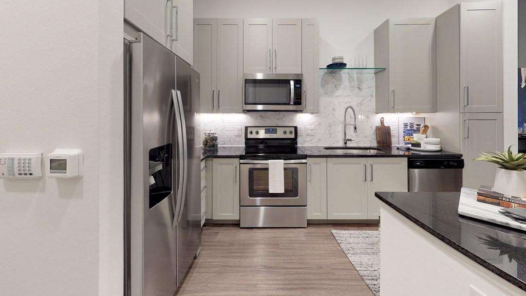 Kitchen with wood cabinets and stainless steel appliances with undermount sink and gooseneck faucet.