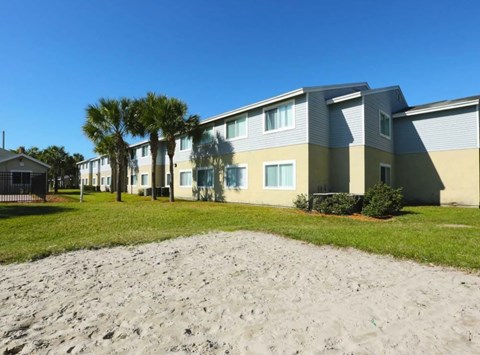 A sandy area in front of a building with a clear blue sky.