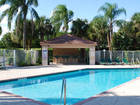 Fenced in Swimming Pool with Sundeck and Lounge Chairs Next to Cabana