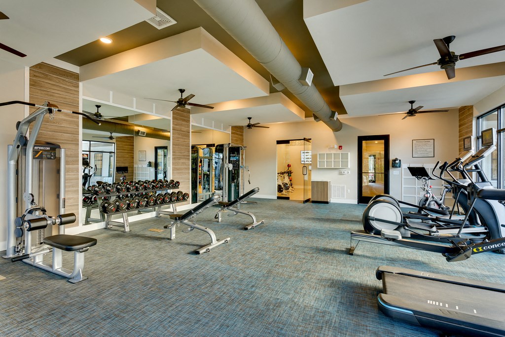 a gym with treadmills and other exercise equipment in a large room with windows