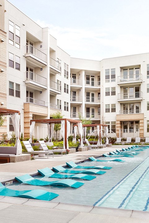 A swimming pool with blue mats in front of apartment buildings.