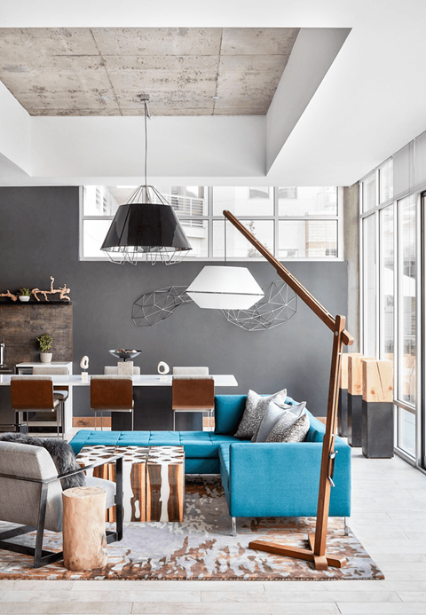 A living room with a blue couch and a wooden floor lamp.