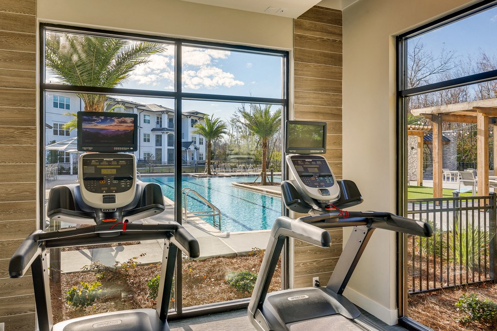 two treadmills in front of a window overlooking a swimming pool