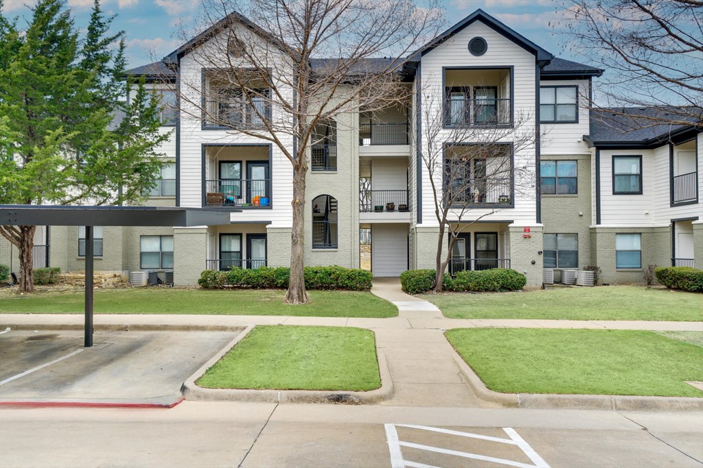 Apartment complex with a parking lot in front.