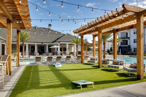 a pool area with lounge chairs and tables under a wooden canopy