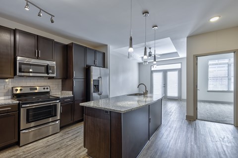A modern kitchen with dark wood cabinets and stainless steel appliances.