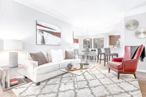 A living room with a white couch, a red chair, and a coffee table at Elan at Mallard Creek Apartment Homes, Charlotte, NC
