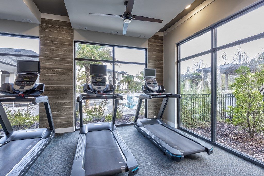 two treadmills in a gym with windows and a pool