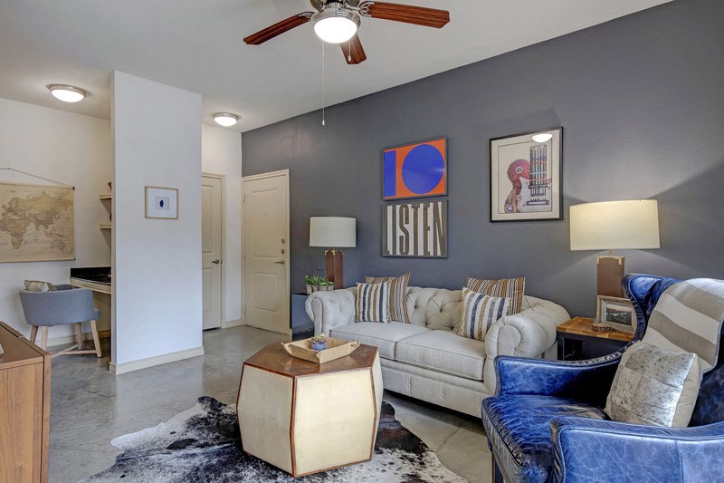 a living room with blue and white furniture and a ceiling fan