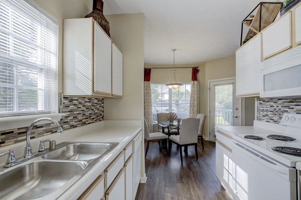 a kitchen with white appliances and a dining room with a table and chairs