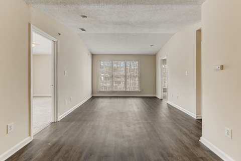 the spacious living room of an empty house with a large window