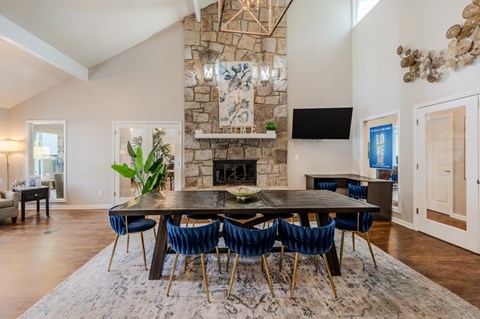 A dining room with a stone fireplace and a large table surrounded by chairs.