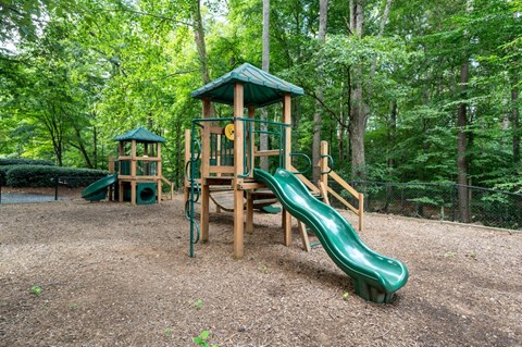 A playground with a green slide and a wooden structure.