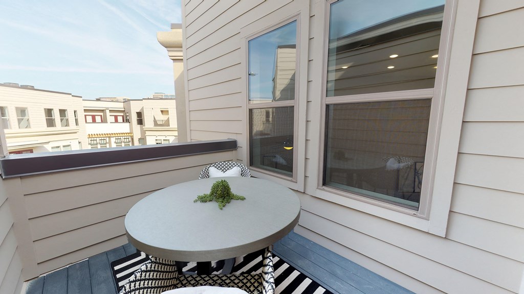 Exterior patio of apartment with small bistro table and chairs on outdoor rug