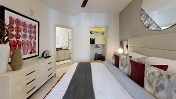 Interior of bedroom with large bed, dresser and decorative mirror facing inside of closet and bathroom - Photo Gallery 44