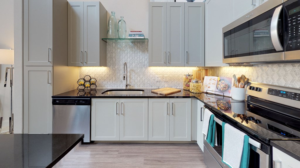 Kitchen with wood cabinets and stainless steel appliances with undermount sink and gooseneck faucet.