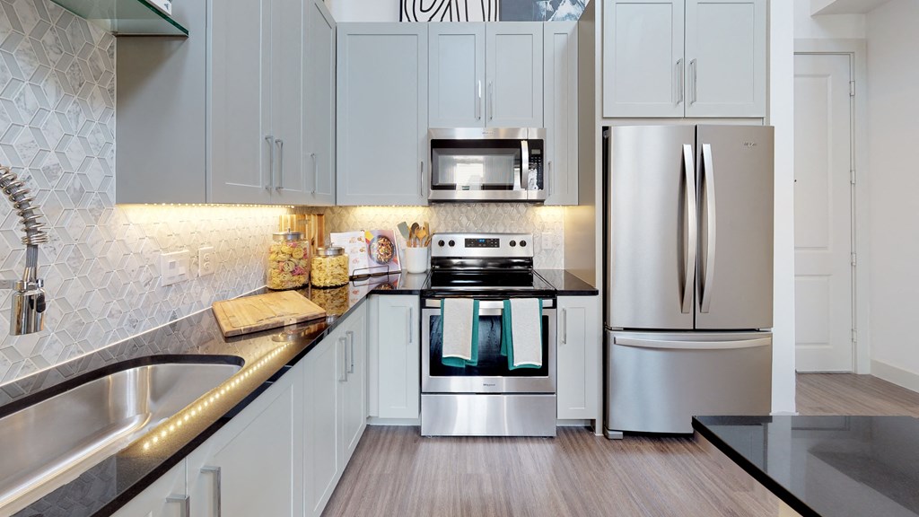 Kitchen with wood cabinets and stainless steel sink and white appliances