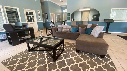 A living room with a brown couch and a glass coffee table.