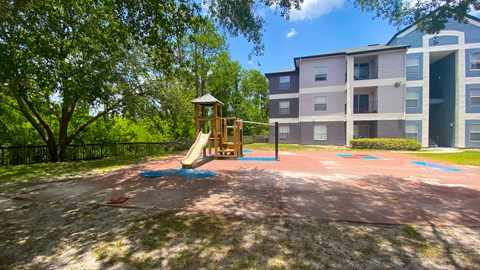 A playground with a slide and a gazebo in the middle of a brick area.